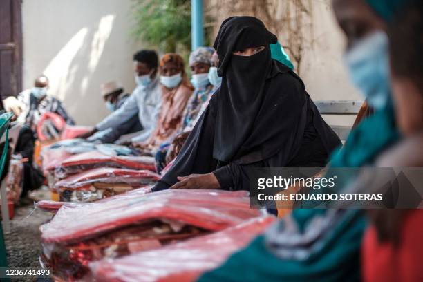 An Ethiopian migrant looks on as she sits next to several items during an assistance packages distribution for migrants at an International...