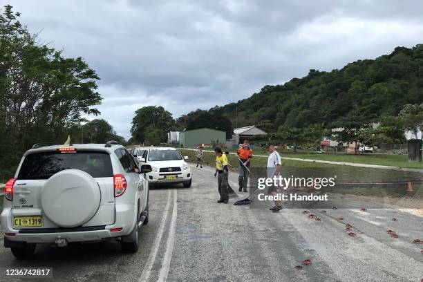 In this handout image provided by Parks Australia, members of the public and Parks Australia staff rack away thousands of red crabs off a road on...