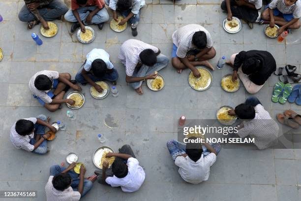 Students eat their mid-day meal during lunch break at a government high school on the outskirts of Hyderabad on November 23 as schools reopen after...