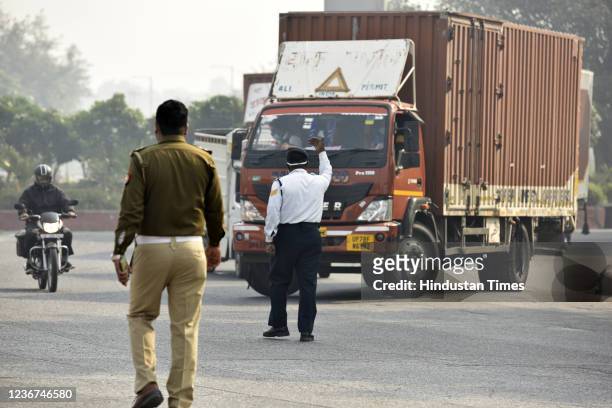 Traffic police personnel stop a truck from entering Delhi near the Mahamaya flyway as only trucks carrying essential services are allowed in...