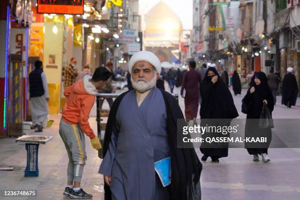 Shiite cleric walks down a street in Iraq's central holy shrine city of Najaf as religious schools reopen after more than two years amid the Covid-19...