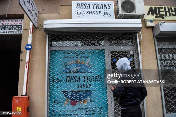 Relative of victims of the bus crash holds his phone in front of the offices of 'Besa Trans' travel agency in Skopje, on November 23, 2021. - North...