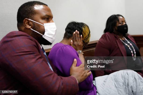 Attorney Lee Merritt consoles Wanda Cooper-Jones, mother of Ahmaud Arbery, as she reacts while seeing photos of her son on a monitor, during the...
