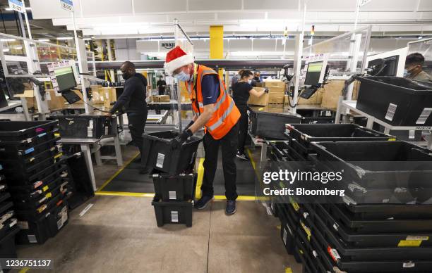 An employee moves plastic crates in the goods inward section of an Amazon.com Inc. Fulfilment center in Swindon, U.K., on Tuesday, Nov. 23, 2021....