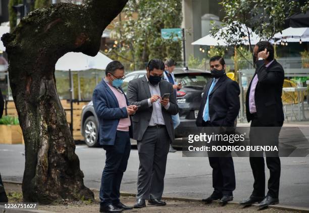 Men use their mobile phones on the street after evacuating a building due to a 4.5 degree quake in Quito, on November 23, 2021.
