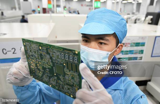 Worker confirms the solder paste printing effect at an SMT production line in Guiyang, Guizhou Province, China, Nov 24, 2021. The chip products...