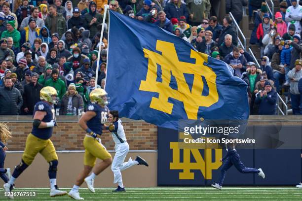 Notre Dame Fighting Irish cheerleader runs onto the field with a Notre Dame Fighting Irish flag after a touchdown play during a game between the...