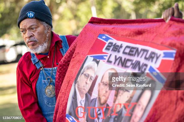 Eric Terrell, vice president of the National Action Network, holds a banner with photos of William Roddie Bryan, Travis McMichael, Greg McMichal and...