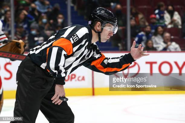 Referee Kendrick Nicholson calls a tripping penalty while officiating between the Chicago Blackhawks and Vancouver Canucks during their NHL game at...