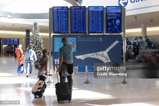 Travelers look at a departure board in Terminal 4 at John F. Kennedy International Airport in New York, U.S., on Wednesday, Nov. 24, 2021. Air...