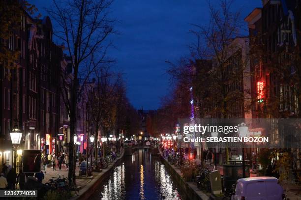 People walk on docks at night in the red quarter in Amsterdam, western Netherlands, on November 24, 2021.