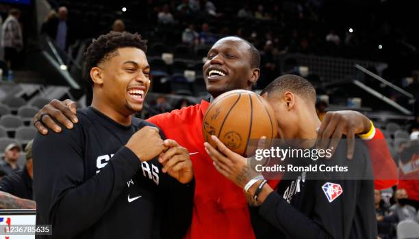 Keldon Johnson and Dejounte Murray of the San Antonio Spurs joke with Gorgui Dieng of the Atlanta Hawks before a game at AT&T Center on November 24,...