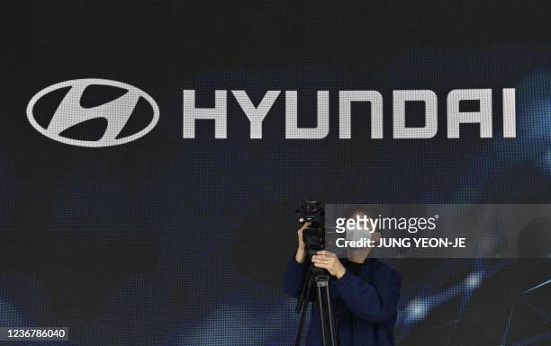 Man takes video footage in front of the logo of South Korean auto-maker Hyundai Motor during a press preview of the Seoul Mobility Show at KINTEX...