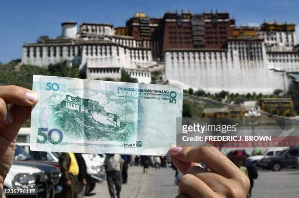 Chinese currency 50-yuan note , depicting the Potala Palace in Tibet, is held for display in front of the Lhasa landmark, 08 August 2002 in Lhasa....