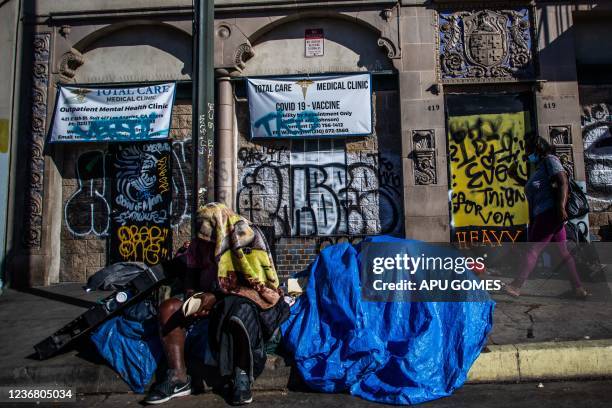 Homeless man sits in the sidewalk in front of the headquarters of the non-profit Midnight Mission, while traditional Thanksgiving meals are served to...