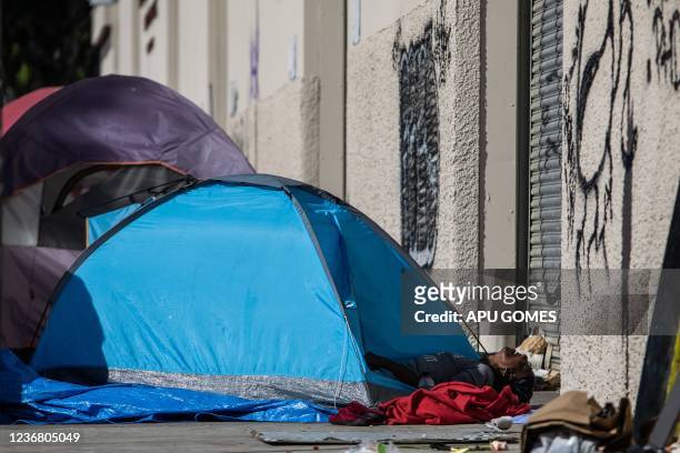 Homeless person lies in their tent on the sidewalk in front of the non-profit Midnight Mission's headquarters, while traditional Thanksgiving meals...