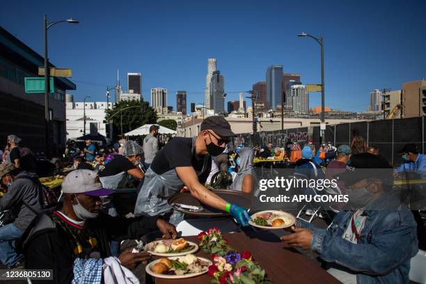 Volunteer serve a plate of food to a homeless man during the traditional Thanksgiving meal served by the non-profit Midnight Mission to nearly 2000...