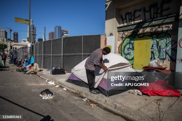 Homeless man zips up his tent in front of the non-profit Midnight Mission's headquarters, while traditional Thanksgiving meals are served to nearly...