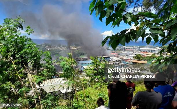 Smoke rises from a burnt out buildings in Honiara's Chinatown on November 26, 2021 after two days of rioting which saw thousands ignore a government...