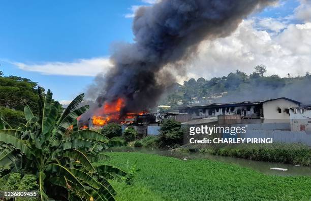 Flames rise from buildings in Honiara's Chinatown on November 26, 2021 as days of rioting have seen thousands ignore a government lockdown order,...