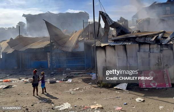 Smoke rises from a burnt out buildings in Honiara's Chinatown on November 26, 2021 after two days of rioting which saw thousands ignore a government...