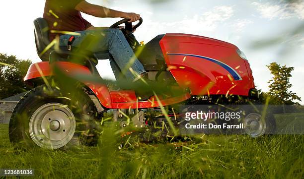 mower with flying grass clippings - grasmaaier stockfoto's en -beelden