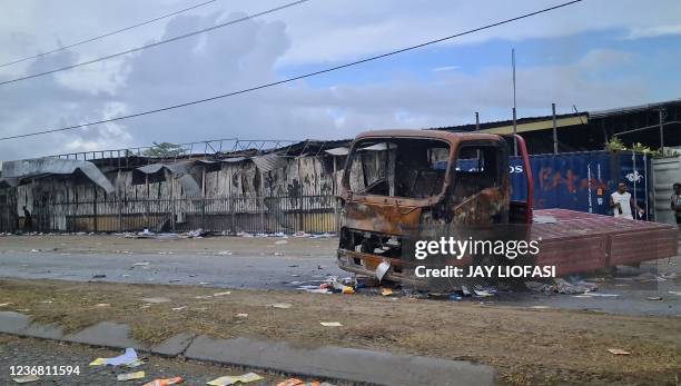 Frame grab from video footage shows a burnt-out truck and damaged buildings in Honiara on November 26 after days of rioting following political...