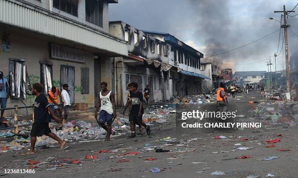 People walk through the Chinatown district of Honiara on the Solomon Islands on November 26 after a third day of violence that saw the prime...