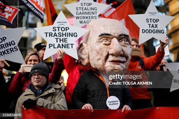 An activist from the Extinction Rebellion climate change group, wearing a mask depicting Jeff Bezos, takes part in a protest outside of Amazon's...