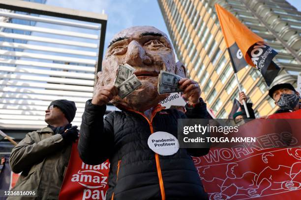 An activist from the Extinction Rebellion climate change group, wearing a mask depicting Jeff Bezos, takes part in a protest outside of Amazon's...