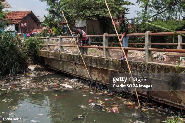 Men net plastic waste to let water flow in the Bojong Citepus River which empties into the Citarum River in Dayeuhkolot. The National Plastic Action...