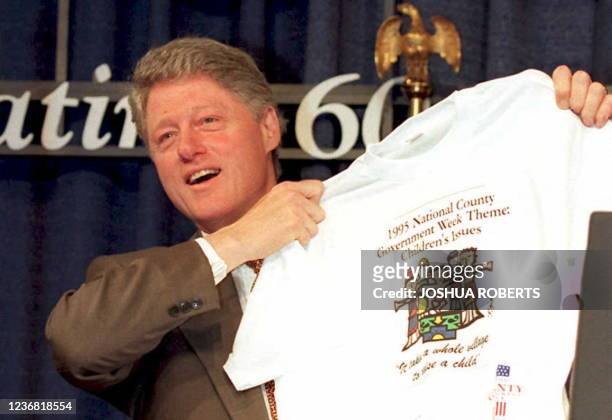 President Bill Clinton holds up a T-shirt given to him at a speaking engagement to the National Association of Counties 07 March in Washington DC....
