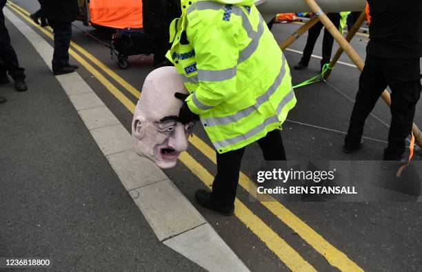 Police officer removes a mask depicting the face of Jeff Bezos, from the Extinction Rebellion climate change activist, during a protest blocking the...