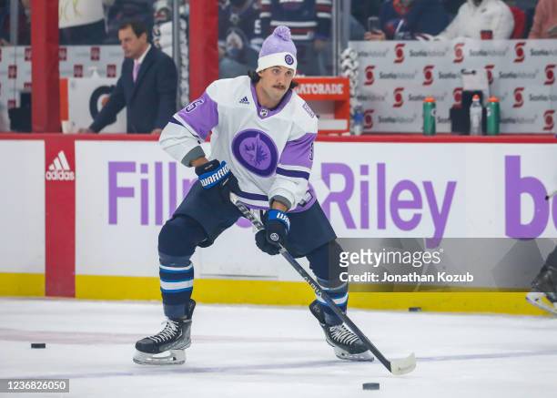 Brenden Dillon of the Winnipeg Jets takes part in the pre-game warm up sporting a lavender jersey in support of Hockey Fights Cancer Night prior to...