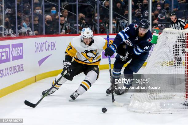 Sidney Crosby of the Pittsburgh Penguins plays the puck around the net while Pierre-Luc Dubois of the Winnipeg Jets gives chase during first period...