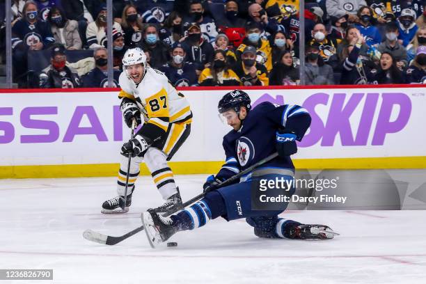 Neal Pionk of the Winnipeg Jets stops the puck as Sidney Crosby of the Pittsburgh Penguins looks on during third period action at Canada Life Centre...