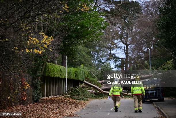 Fire fighters arrive to inspect the damage as residents clear branches from a fallen tree in Birkenhead, north west England on November 27 as "Storm...