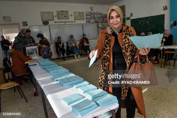 Woman picks up a ballot while voting in the Algerian local elections at a polling station in the capital Algiers on November 27, 2021. - Algerians on...