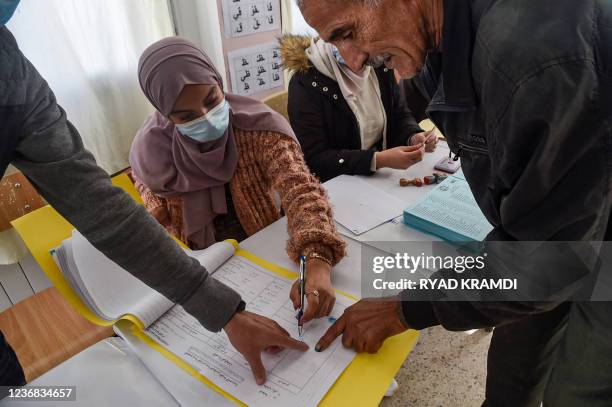 Man signs a register after voting in the Algerian local elections at a polling station in the capital Algiers on November 27, 2021. - Algerians on...