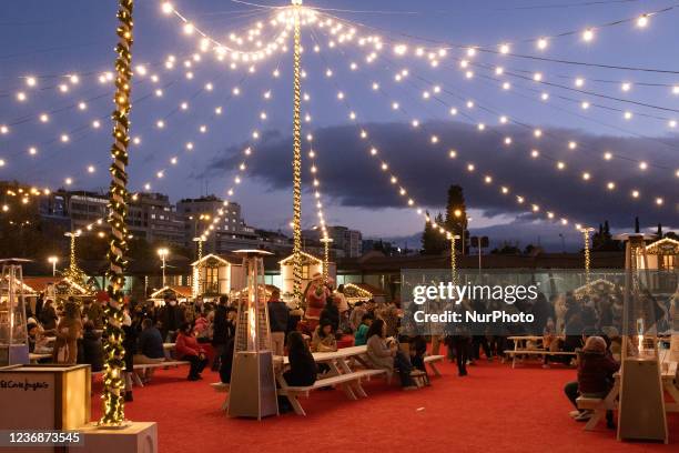 People at a Christmas market with Christmas lights in Madrid, Spain.