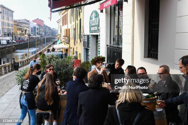 People sit on a restaurant outdoor at the Navigli in Milan, Italy on November 26, 2021.