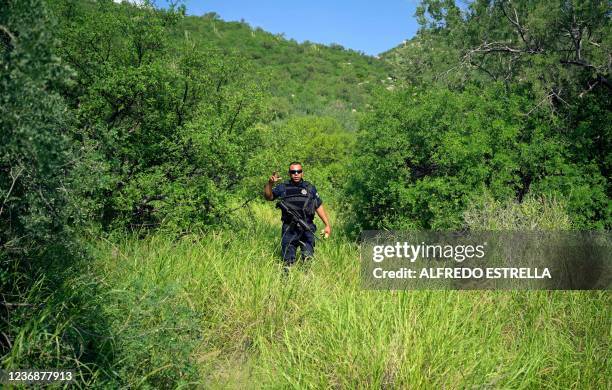 State policeman looks after members of the Madres Buscadoras de Sonora civil organization as they search for human remains, in the outskirts of...