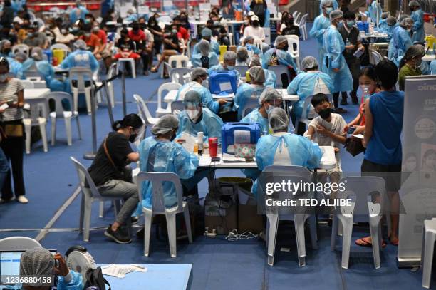 Medical workers in protective suits administer vaccines at a colisium in Makati City, suburban Manila on November 29 as the Southeast Asian nation...