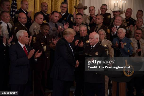 President Donald Trump and Vice President Mike Pence meet with sheriffs from across the country in the East Room of the White House in Washington,...