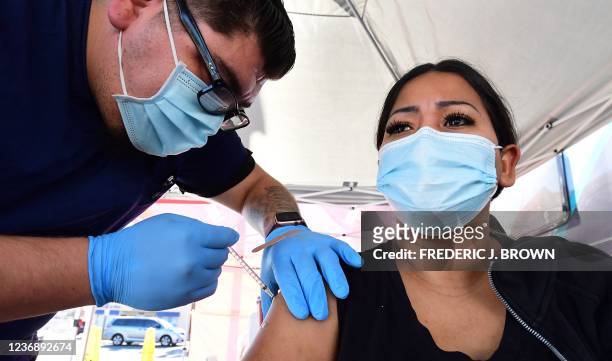 Carmen Penaloza receives her first dose of the Pfizer Covd-19 vaccine at a pop-up clinic offering vaccines and booster shots in Rosemead, California...
