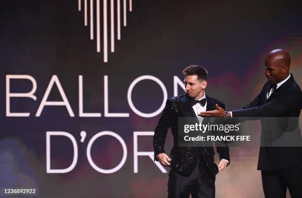 Paris Saint-Germain's Argentine forward Lionel Messi reacts with Ivorian former football player and evening host Didier Drogba after being awarded...