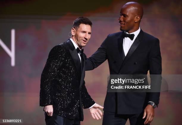 Paris Saint-Germain's Argentine forward Lionel Messi reacts with Ivorian former football player and evening host Didier Drogba after being awarded...