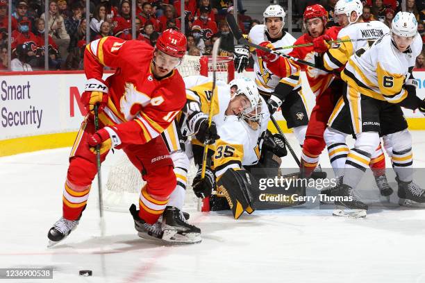 Mikael Backlund of the Calgary Flames battles for the puck against the Pittsburgh Penguins at Scotiabank Saddledome on November 29, 2021 in Calgary,...