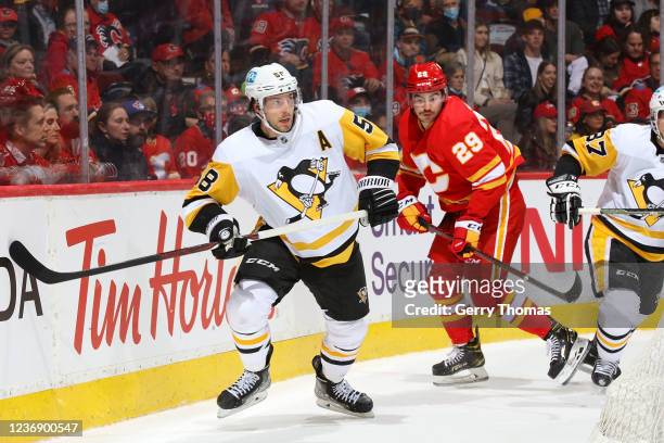 Dilon Dube of the Calgary Flames battles against Kris Letang of the Pittsburgh Penguins at Scotiabank Saddledome on November 29, 2021 in Calgary,...