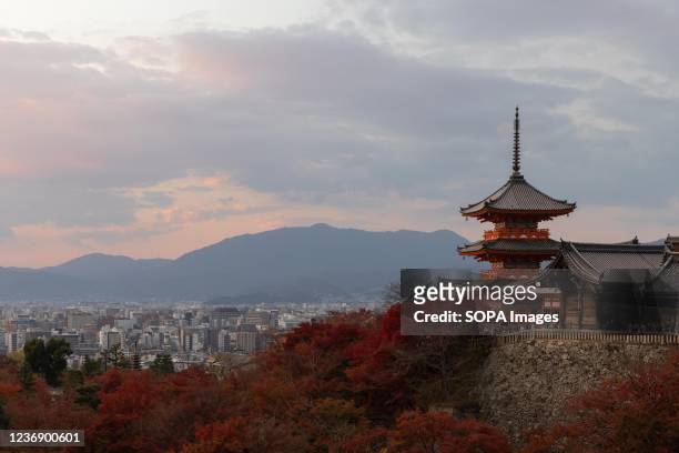 Three-storied Pagoda seen inside Kiyomizu-dera Buddhist temple in Kyoto surrounded by autumn colored leaves.